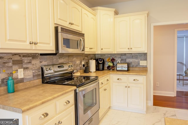 kitchen featuring baseboards, decorative backsplash, light countertops, appliances with stainless steel finishes, and marble finish floor