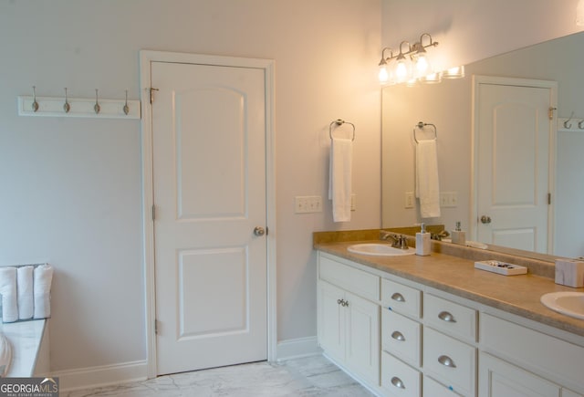 bathroom featuring double vanity, marble finish floor, baseboards, and a sink