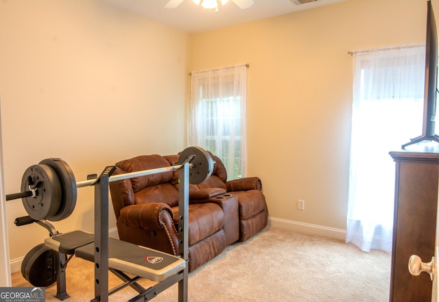 exercise area featuring a ceiling fan, visible vents, light colored carpet, and baseboards