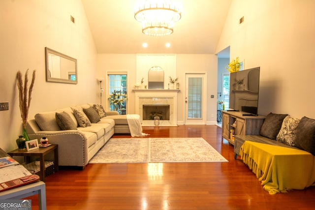 living room with a premium fireplace, a chandelier, high vaulted ceiling, and dark hardwood / wood-style floors