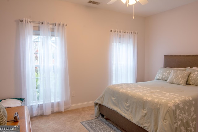 bedroom featuring light colored carpet, a ceiling fan, baseboards, and multiple windows