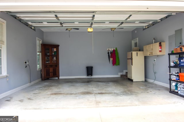 garage featuring baseboards, a garage door opener, and freestanding refrigerator