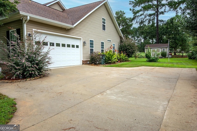 view of home's exterior with a lawn, roof with shingles, and concrete driveway