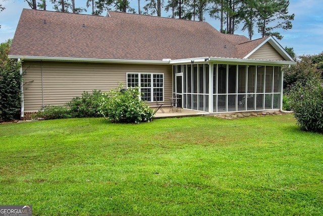 rear view of house with a lawn, a shingled roof, and a sunroom