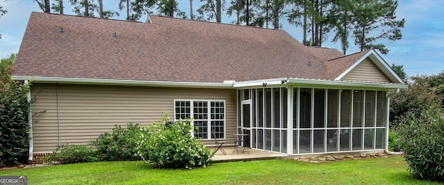 back of property with a patio, a yard, a sunroom, and a shingled roof