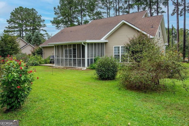 rear view of house with a yard, a shingled roof, and a sunroom