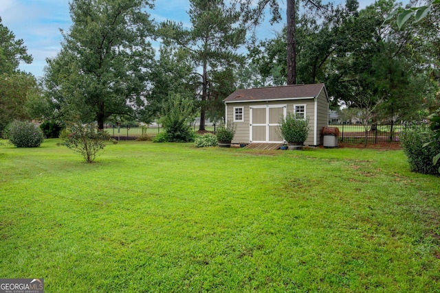 view of yard with a storage unit, an outbuilding, and fence