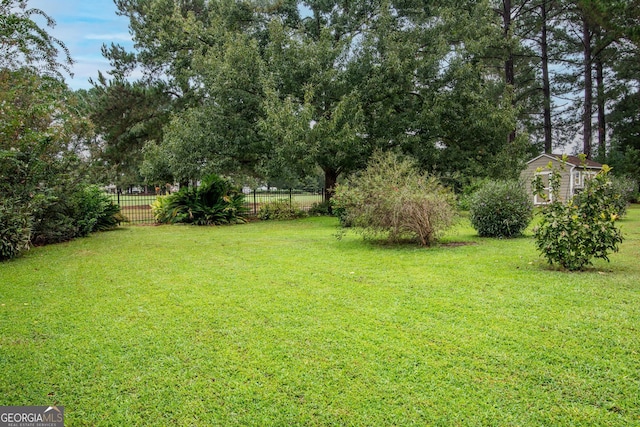 view of yard with a storage shed, an outdoor structure, and fence