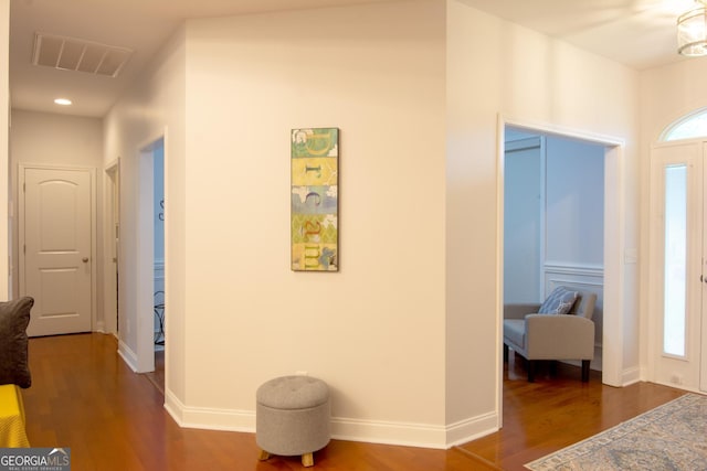 corridor featuring plenty of natural light, wood finished floors, visible vents, and baseboards