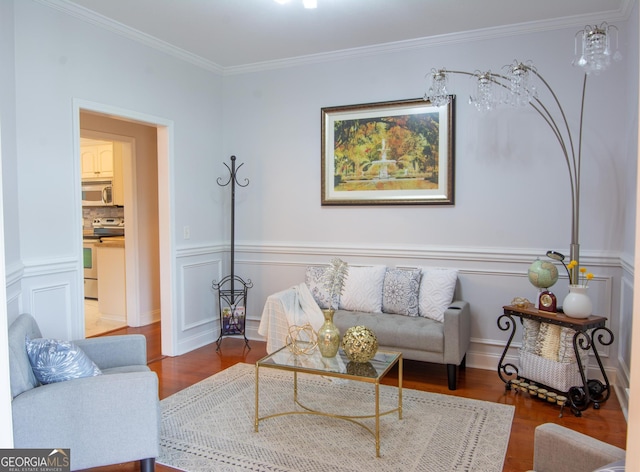 living area featuring a wainscoted wall, ornamental molding, a decorative wall, and wood finished floors