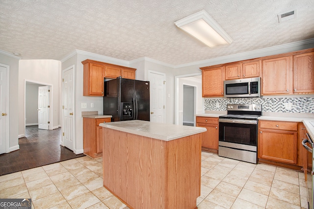 kitchen with ornamental molding, a center island, light wood-type flooring, and appliances with stainless steel finishes