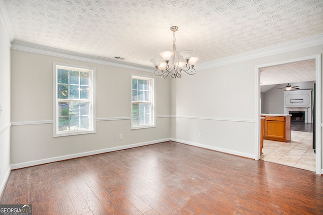 spare room featuring crown molding, light hardwood / wood-style flooring, ceiling fan with notable chandelier, and a textured ceiling