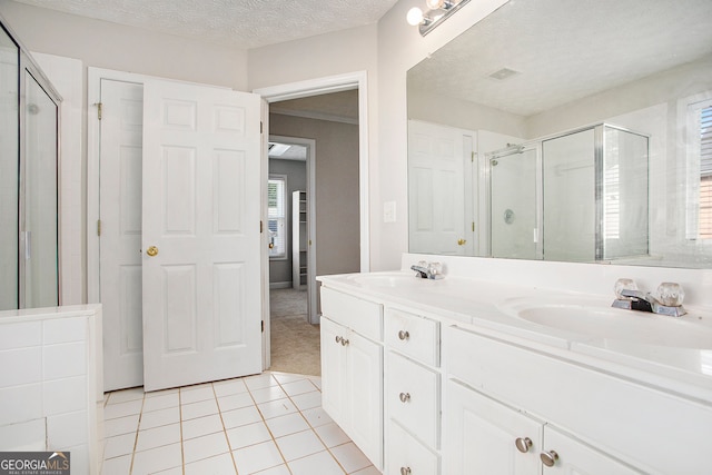 bathroom with vanity, a textured ceiling, tile patterned flooring, and a shower with door