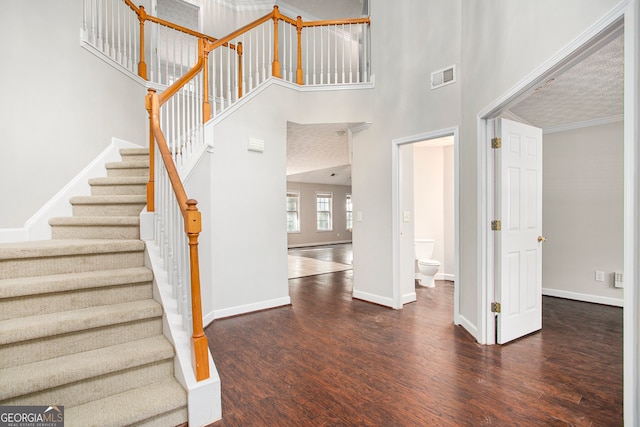 interior space with a textured ceiling, hardwood / wood-style flooring, and a high ceiling