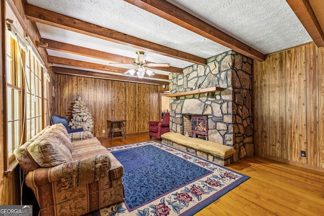 sitting room with a textured ceiling, hardwood / wood-style flooring, beam ceiling, and ceiling fan