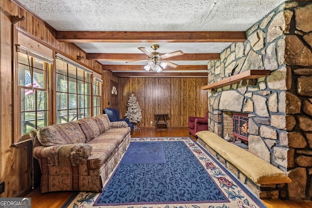 living room featuring hardwood / wood-style floors, ceiling fan, wood walls, and a textured ceiling