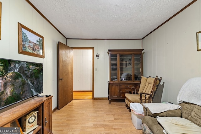 living room with a textured ceiling, crown molding, and light hardwood / wood-style flooring