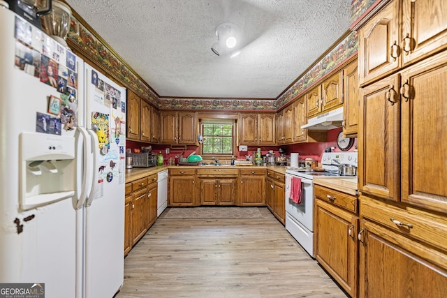 kitchen featuring light wood-type flooring, white appliances, sink, and a textured ceiling