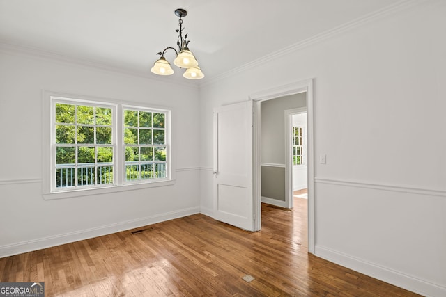 unfurnished room featuring crown molding, hardwood / wood-style floors, and a notable chandelier