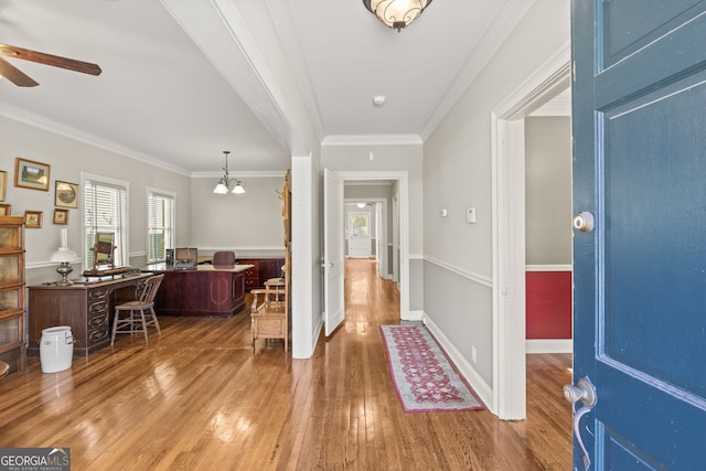 foyer entrance with ceiling fan with notable chandelier, wood-type flooring, and ornamental molding