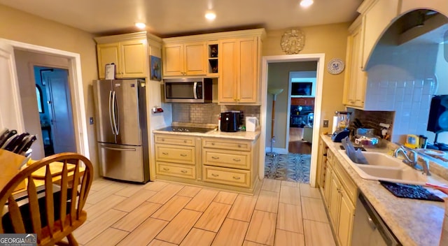 kitchen featuring backsplash, light hardwood / wood-style flooring, appliances with stainless steel finishes, light stone countertops, and sink