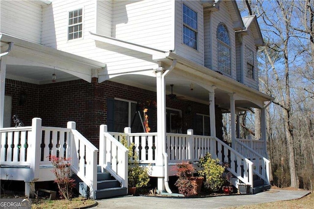 view of side of home featuring brick siding and covered porch