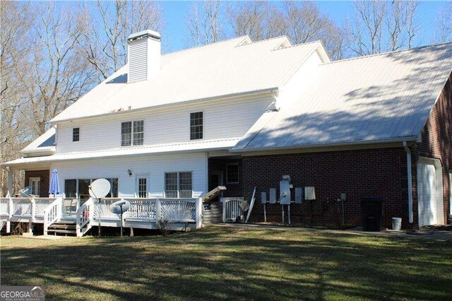 rear view of house featuring a wooden deck and a lawn