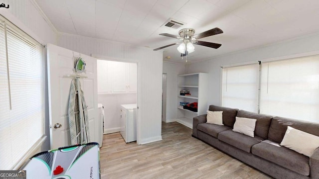 living room with washing machine and clothes dryer, crown molding, ceiling fan, and light wood-type flooring