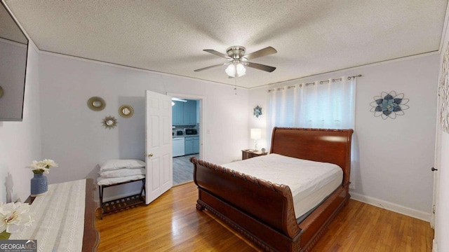 bedroom with a textured ceiling, connected bathroom, ceiling fan, and light hardwood / wood-style floors