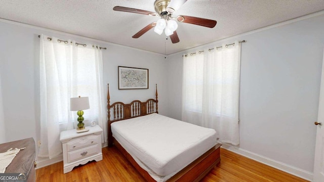 bedroom featuring a textured ceiling, ceiling fan, light wood-type flooring, and multiple windows