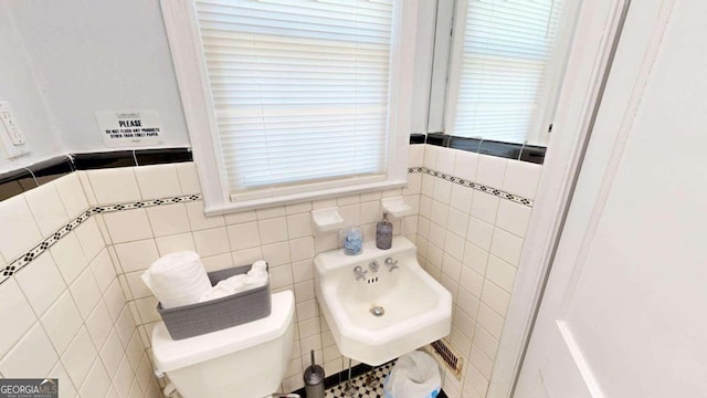 bathroom featuring tile walls, toilet, and sink