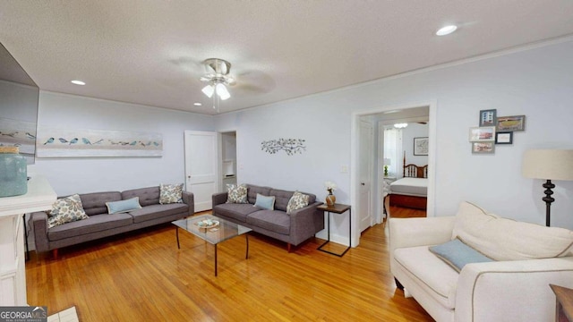 living room with a textured ceiling, ceiling fan, and light hardwood / wood-style floors