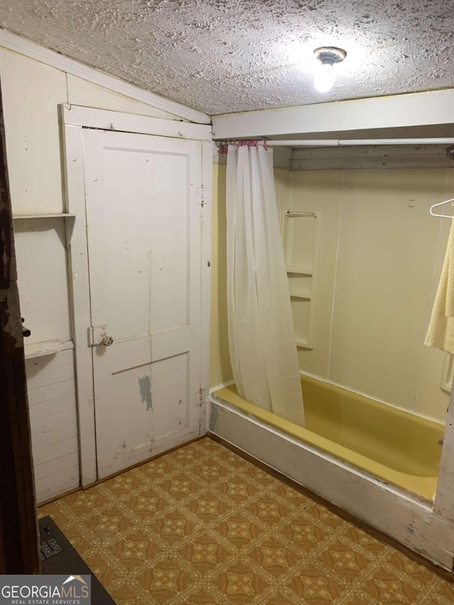 bathroom with lofted ceiling, a textured ceiling, and shower / bathtub combination with curtain