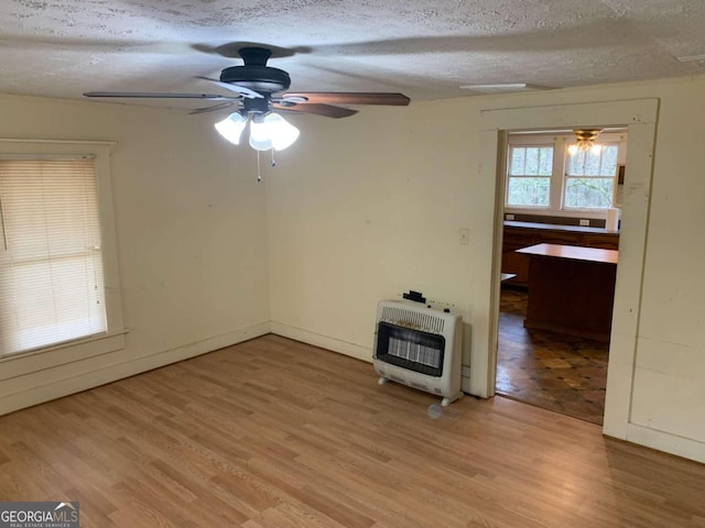 unfurnished living room with hardwood / wood-style floors, ceiling fan, heating unit, and a textured ceiling