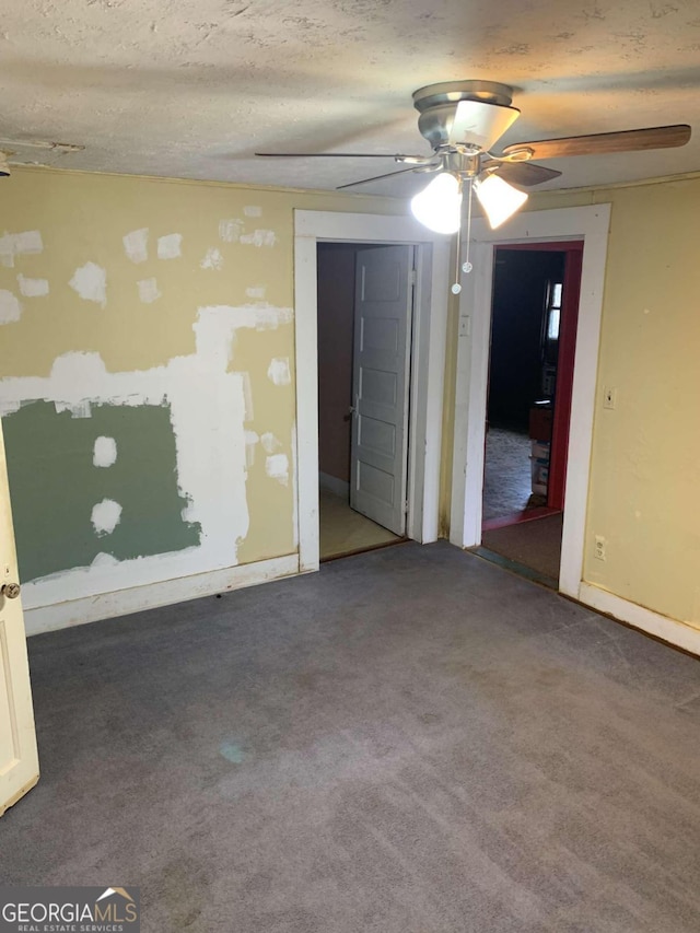 carpeted spare room featuring ceiling fan and a textured ceiling