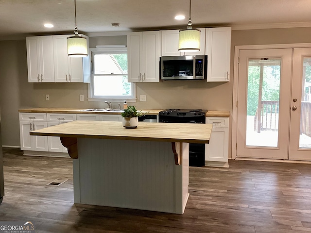 kitchen featuring wood counters, black electric range oven, pendant lighting, and white cabinets