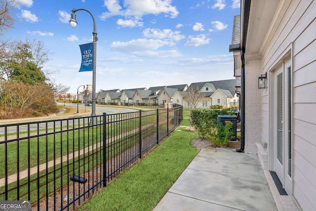 view of community featuring a lawn, fence, and a residential view