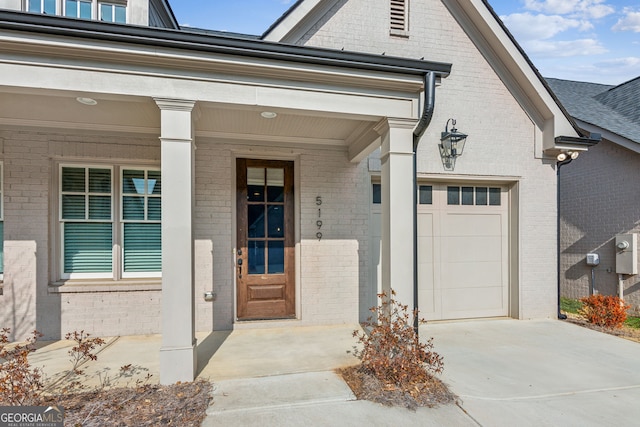 property entrance with a garage, brick siding, driveway, and a porch