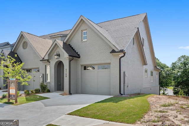 view of front of house featuring brick siding, a shingled roof, a front yard, a garage, and driveway