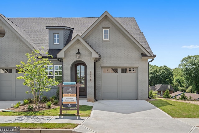 view of front facade featuring a shingled roof, brick siding, driveway, and an attached garage