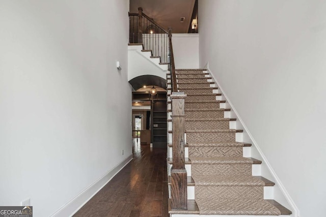 staircase with a towering ceiling and hardwood / wood-style floors