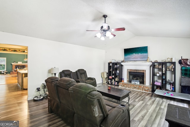 living room with ceiling fan, vaulted ceiling, a fireplace, and hardwood / wood-style floors