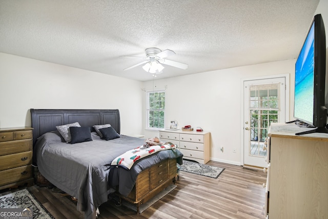 bedroom with access to outside, light hardwood / wood-style flooring, a textured ceiling, and ceiling fan