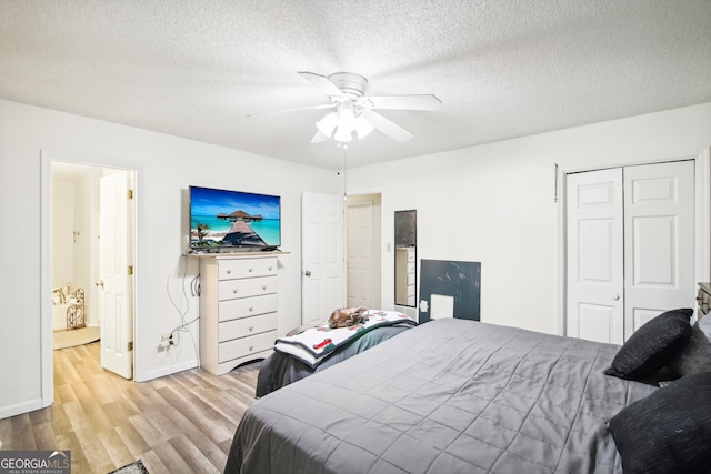 bedroom featuring a closet, a textured ceiling, light wood-type flooring, and ceiling fan