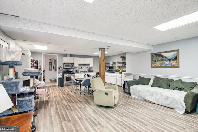 living room with light hardwood / wood-style floors and a drop ceiling