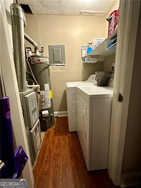 washroom with gas water heater, a textured ceiling, washing machine and clothes dryer, electric panel, and dark hardwood / wood-style floors