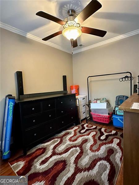 bedroom with ornamental molding, ceiling fan, and dark hardwood / wood-style floors