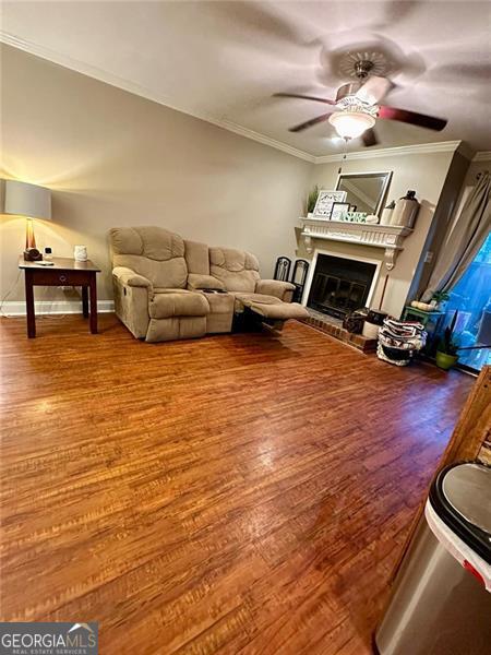 living room featuring ornamental molding, wood-type flooring, and ceiling fan