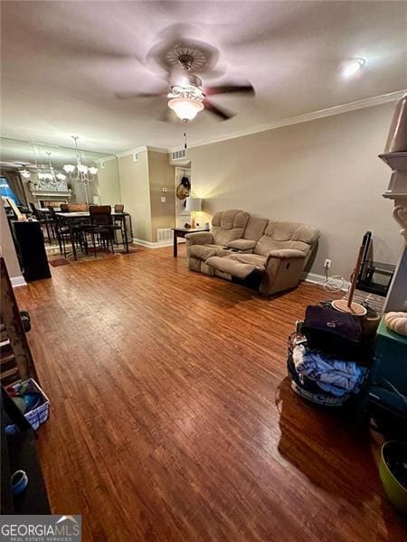 living room featuring ceiling fan with notable chandelier, ornamental molding, and dark hardwood / wood-style floors