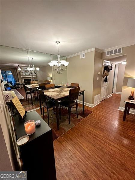 dining room with ornamental molding, dark hardwood / wood-style floors, and a chandelier